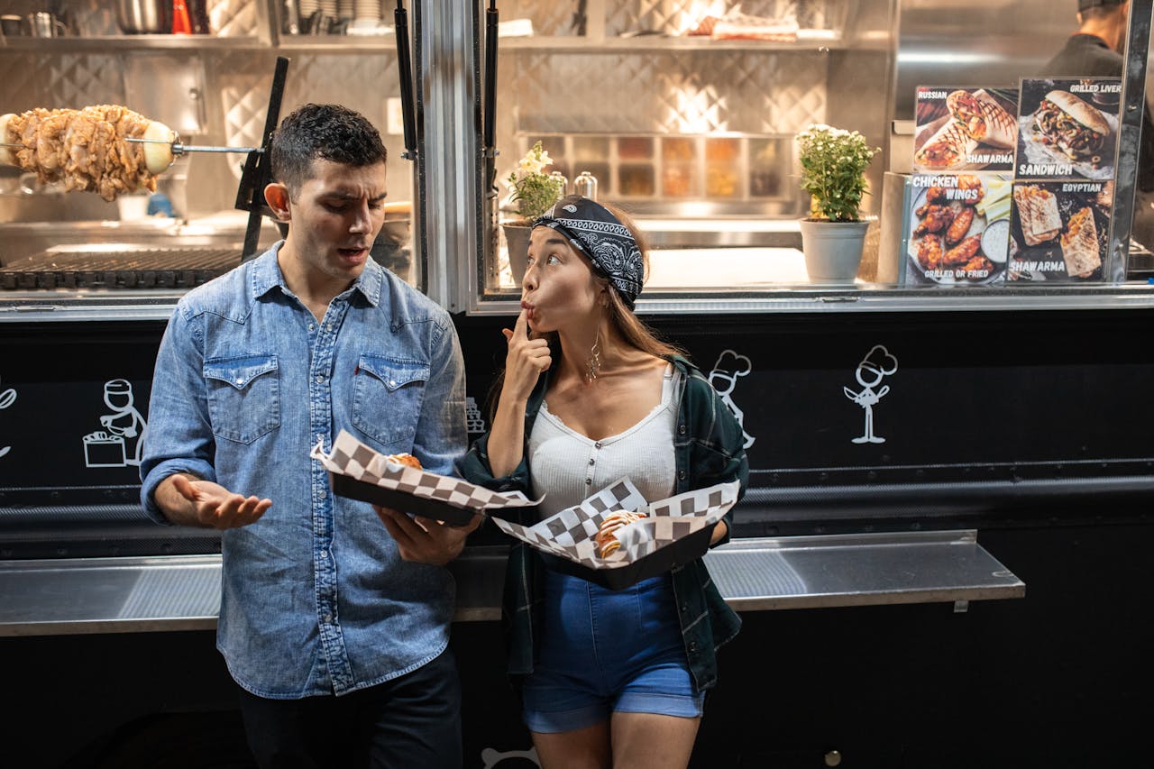 A couple enjoys street food from a food truck at night, sharing fun moments.